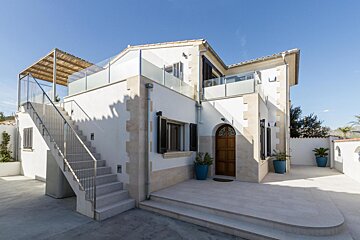A white house with stairs leading up to the second floor