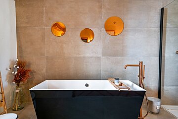 A bathroom with a bathtub and three mirrors on the wall