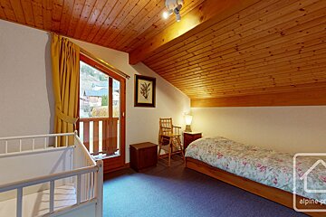A bedroom with a crib and a bed with alpine property written on the bottom