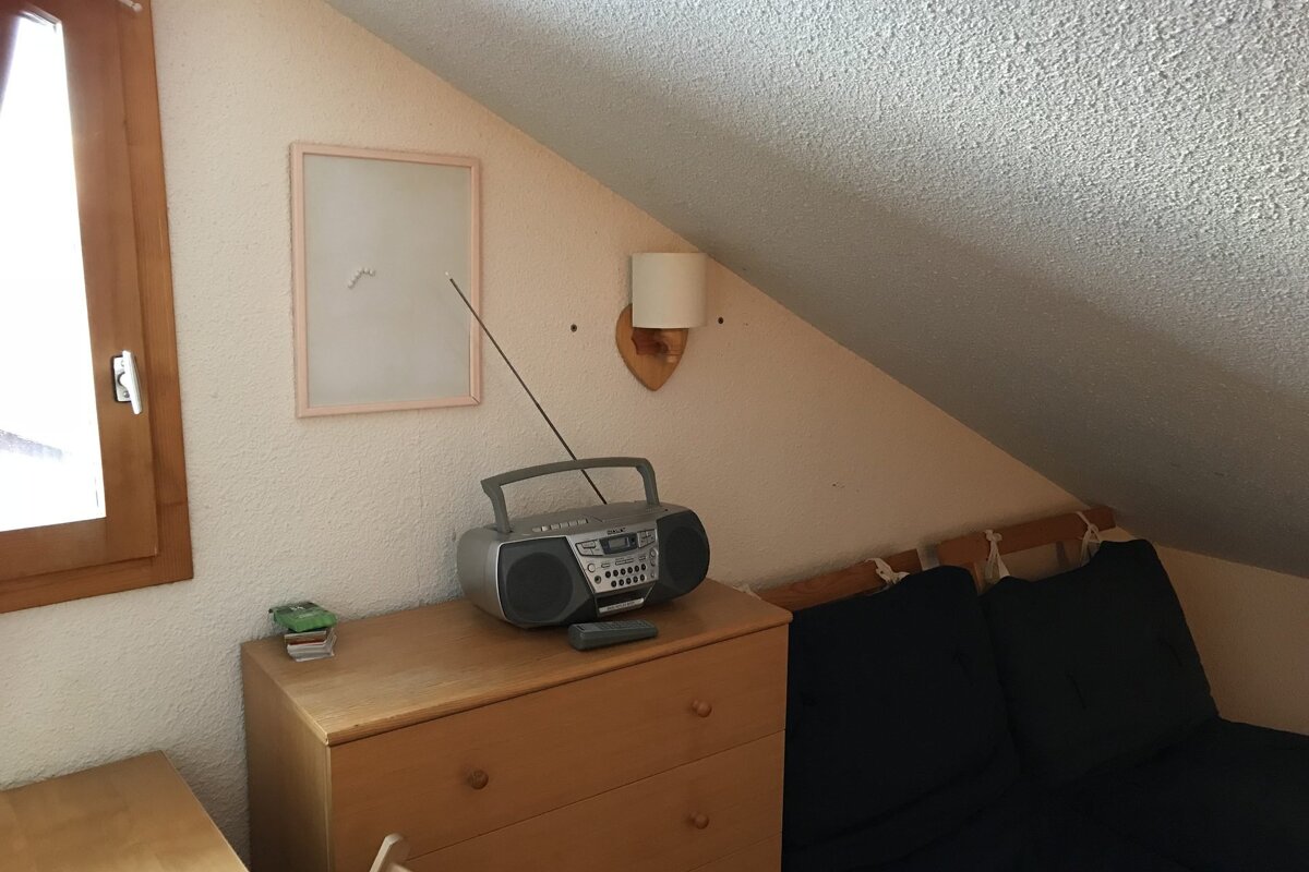 A small radio is sitting on a wooden dresser