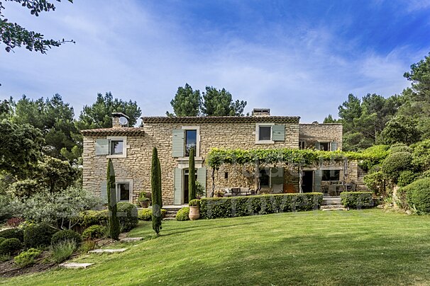 A large stone house with a lush green lawn in front of it