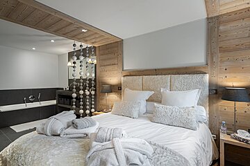 A bedroom with a large bed and a painting on the wall