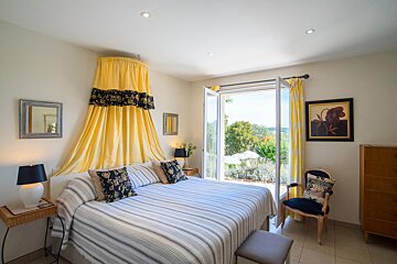 A bedroom with a yellow canopy over the bed