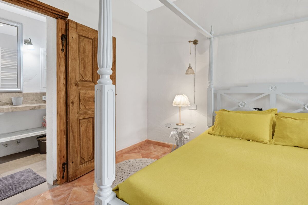 A bedroom with a canopy bed and yellow sheets