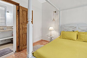 A bedroom with a canopy bed and yellow sheets