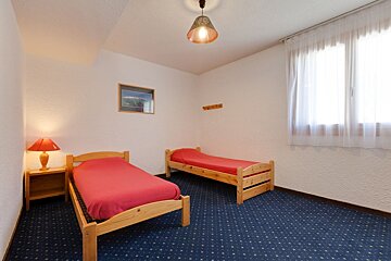 A bedroom with two beds and a lamp