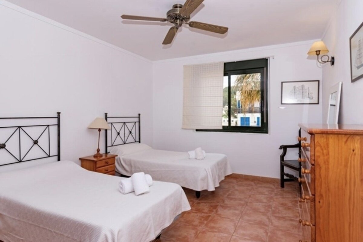 A bedroom with two beds and a ceiling fan