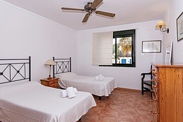 A bedroom with two beds and a ceiling fan