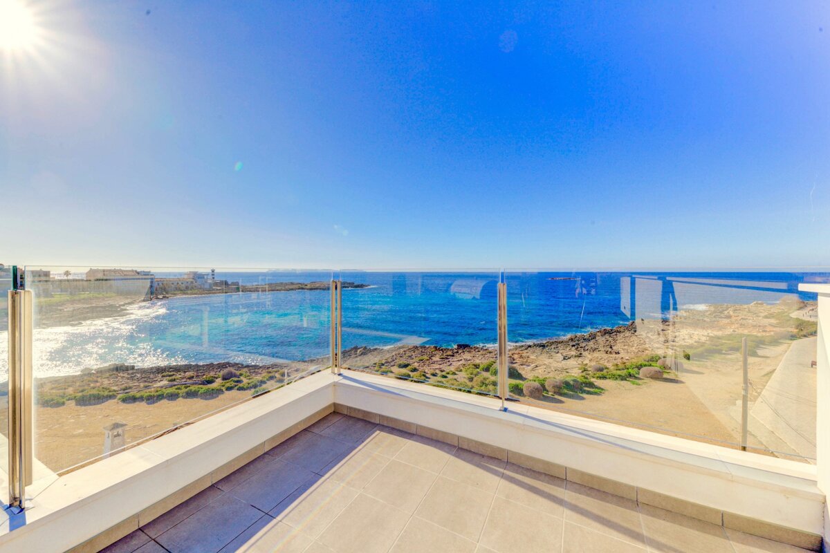 A balcony with a glass railing overlooking the ocean