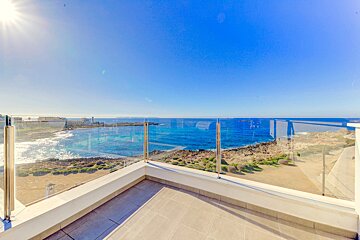 A balcony with a glass railing overlooking the ocean