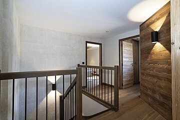 A wooden hallway with a staircase and a door