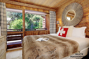 A bedroom with a swiss flag pillow on the bed