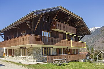 A large wooden house with a yellow arrow pointing to the balcony