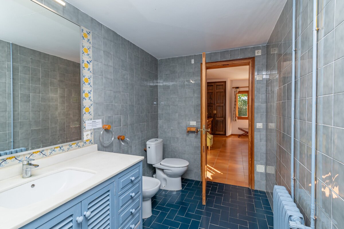 A bathroom with blue tiles and a toilet and sink