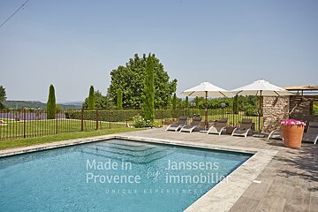 A large swimming pool is surrounded by chairs and umbrellas and says made in provence
