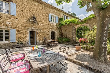 A patio with a table and chairs in front of a stone building