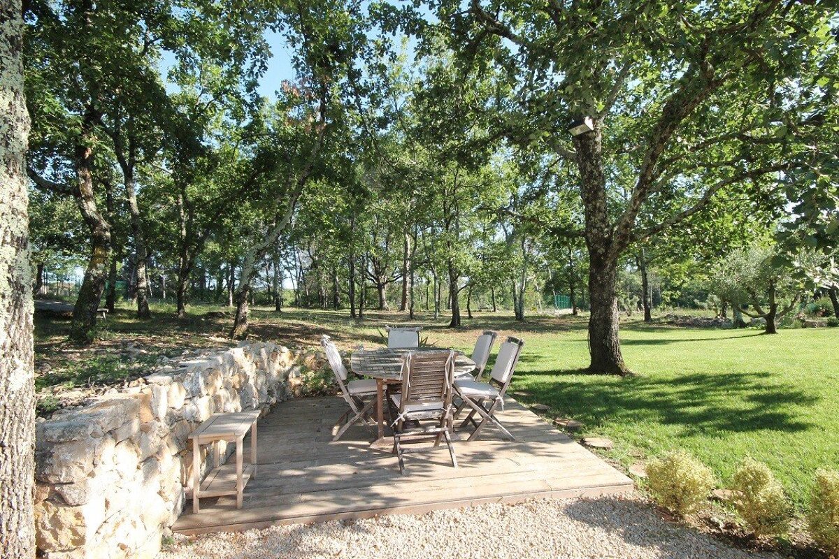 A patio with a table and chairs under trees