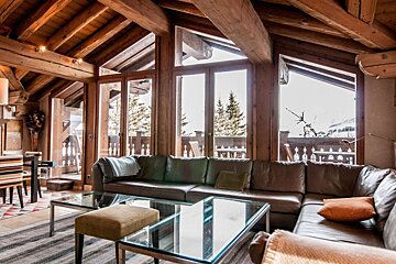 A living room with a large sectional couch and a glass coffee table