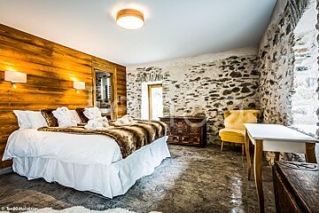 A bedroom with a stone wall and a large bed