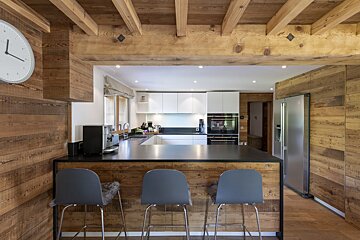A kitchen with wooden walls and a clock that shows the time as 4:20