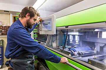 A man in a blue shirt is working on a green machine