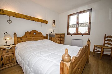 A bedroom with a wooden bed dresser and chair