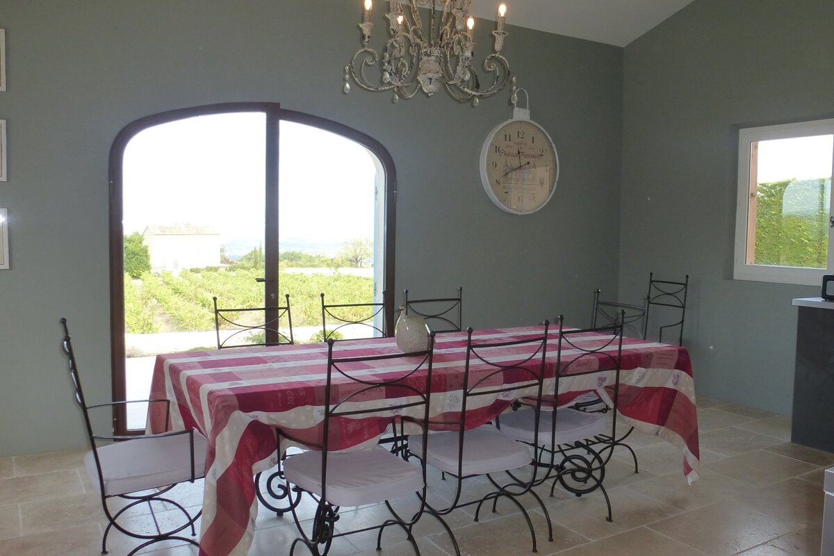 A dining room with a table and chairs and a clock on the wall that says 12:15