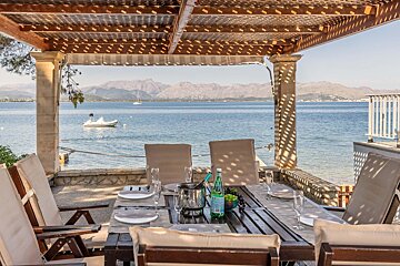 A pergola overlooking a body of water with mountains in the background