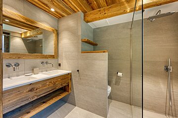 A bathroom with two sinks and a walk in shower