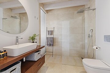 A bathroom with a walk in shower and a sink