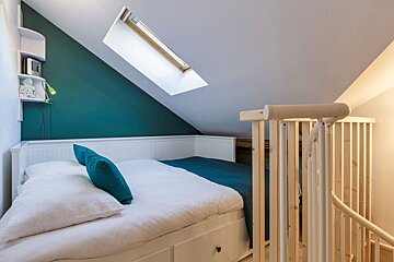 A bedroom with a bed and stairs leading up to it
