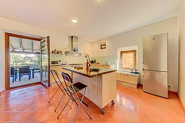 A kitchen with a large island and a stainless steel refrigerator