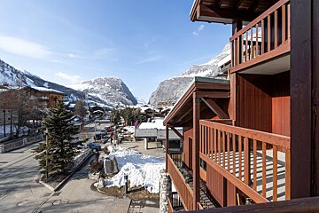 A balcony overlooking a snowy valley with mountains in the background