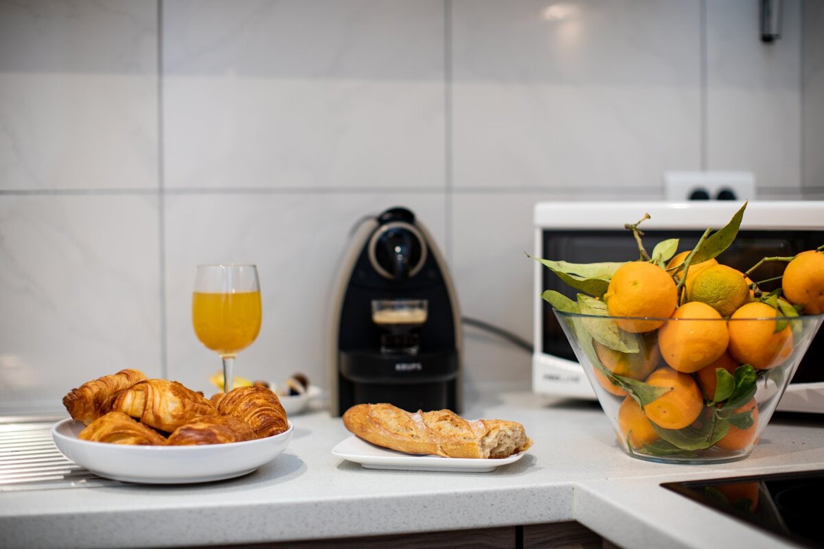 A glass of orange juice sits next to a bowl of oranges