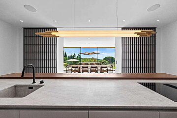 A kitchen with a sink and a dining room in the background