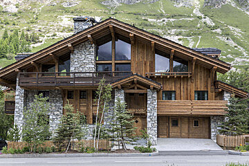 A large stone and wood house with a mountain in the background