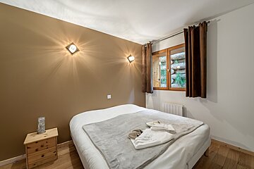 A bedroom with a bed a nightstand and a window