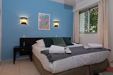 A bedroom with a bed and a picture of a flamingo on the wall