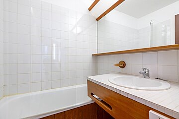 A bathroom with white tiles and a sink and bathtub