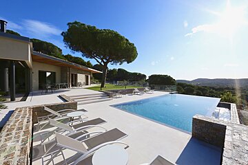 A large swimming pool is surrounded by chairs and tables