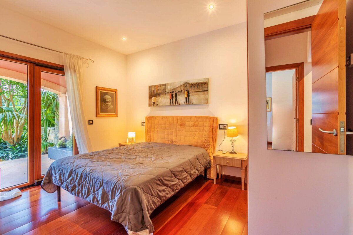 A bedroom with a painting on the wall above the bed