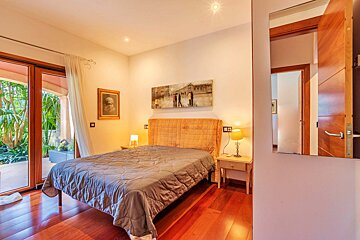 A bedroom with a painting on the wall above the bed