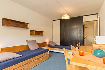 A bedroom with two beds and a table and chairs