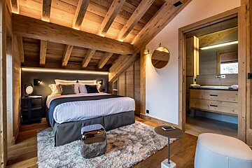 A bedroom with a large bed and a round mirror