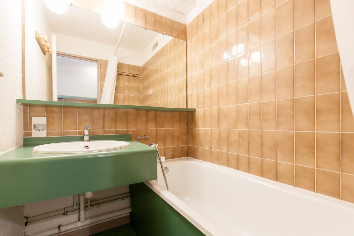 A bathroom with a green sink and a bathtub