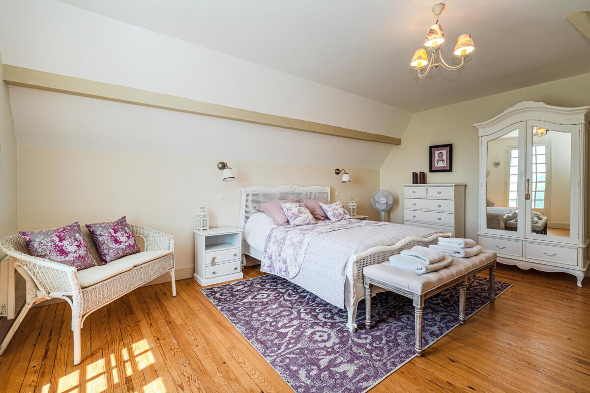 A bedroom with a purple rug and white furniture