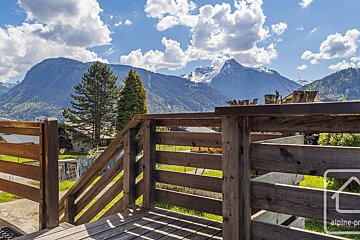 A wooden railing with a mountain in the background and the word alpine on it