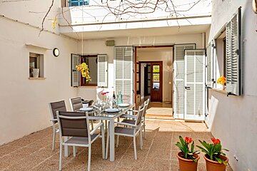 A patio with a table and chairs and potted flowers
