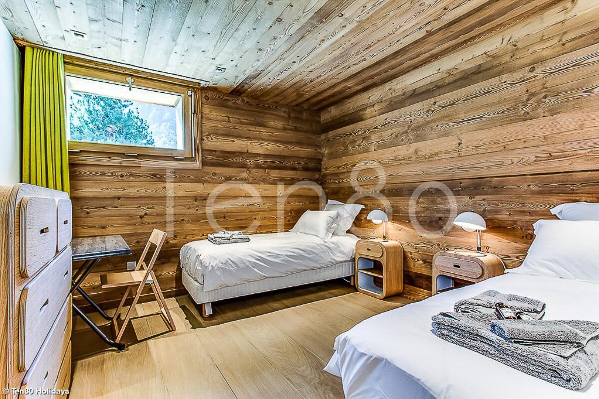 A bedroom with two beds and a dresser with the number 80 on the wall