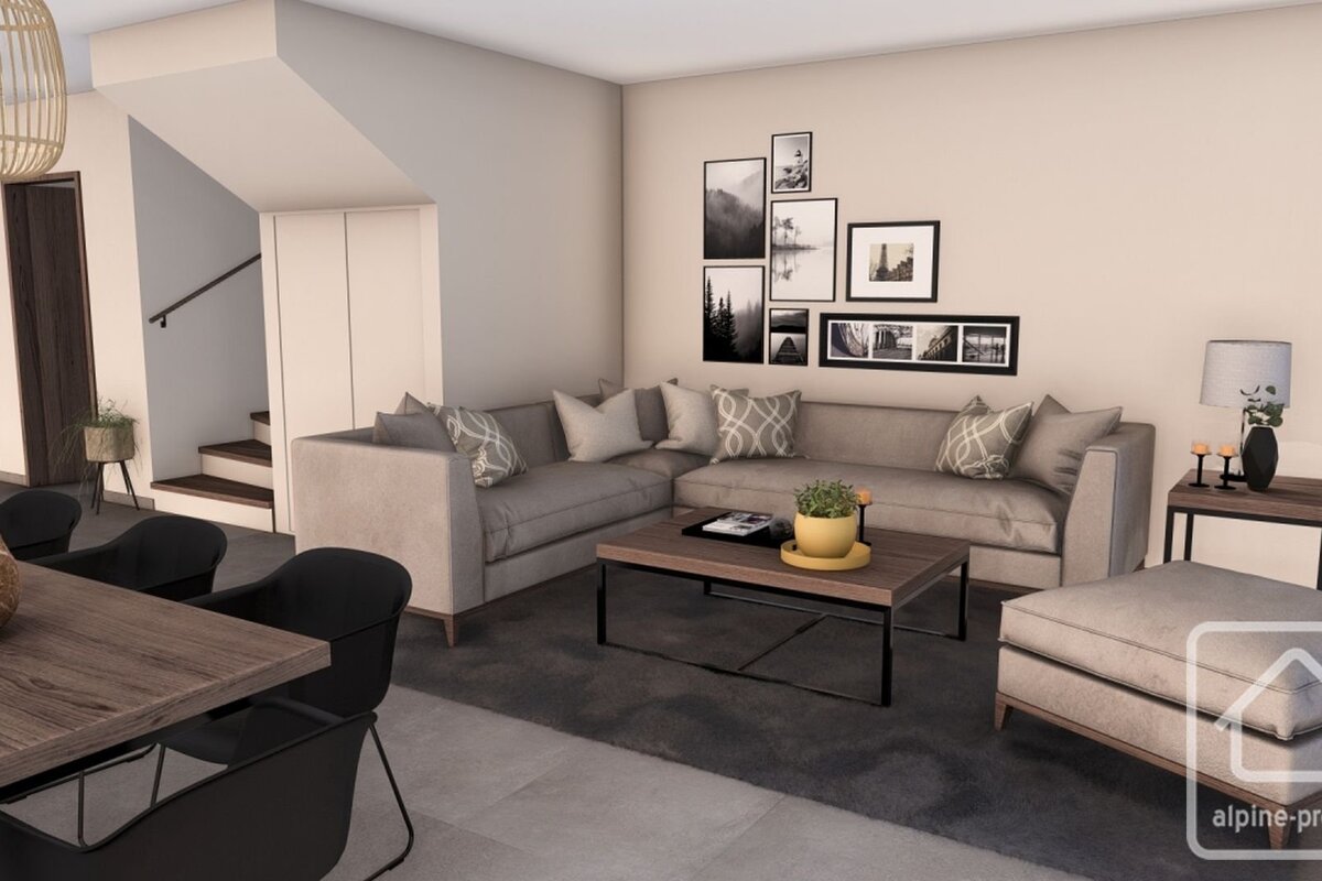A modern, open-plan living room with a gray sectional sofa, coffee table, and a gallery wall. A dining area and staircase are also visible.